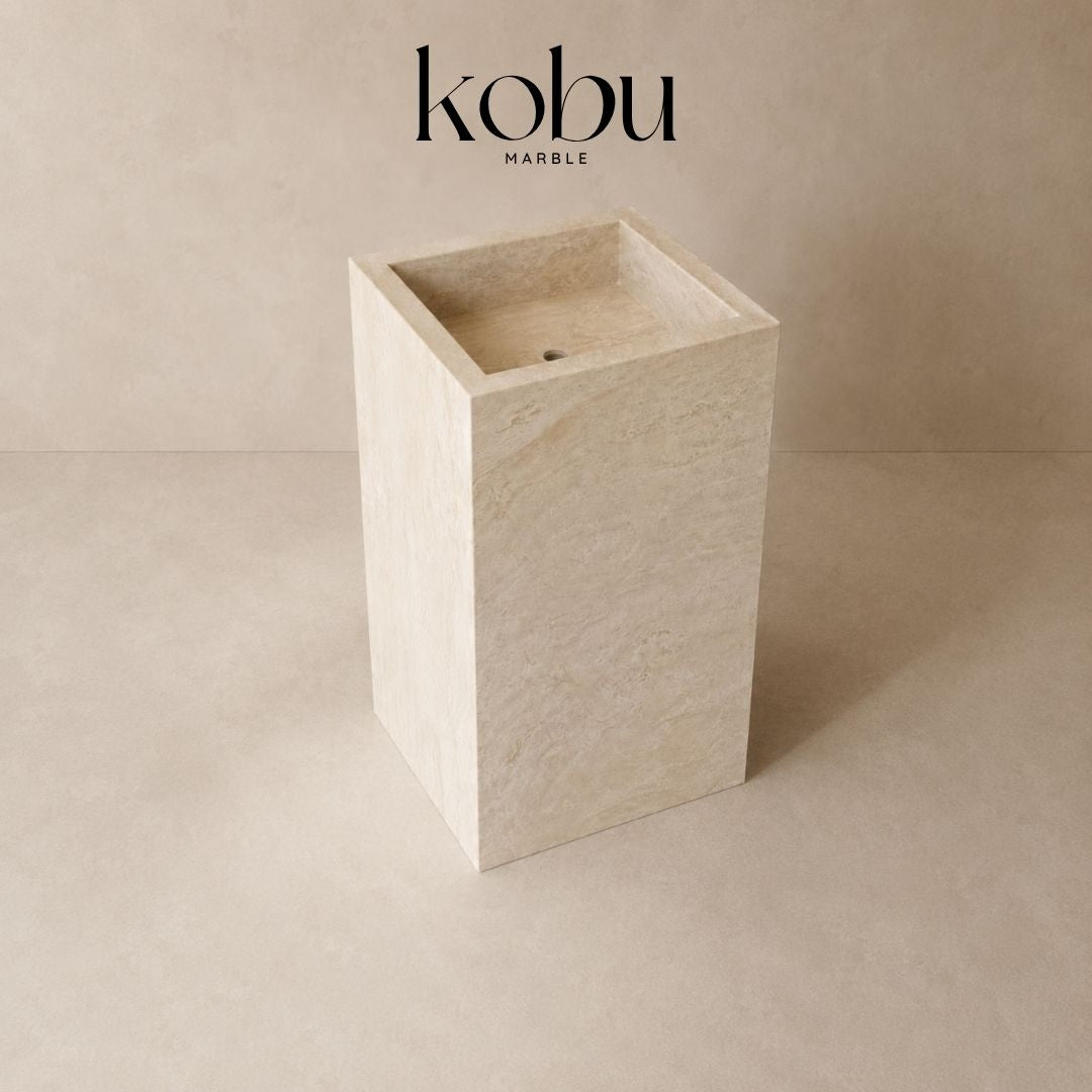 Angled view of a 24-inch travertine stone pedestal sink showing its natural stone texture and sculptural form.
