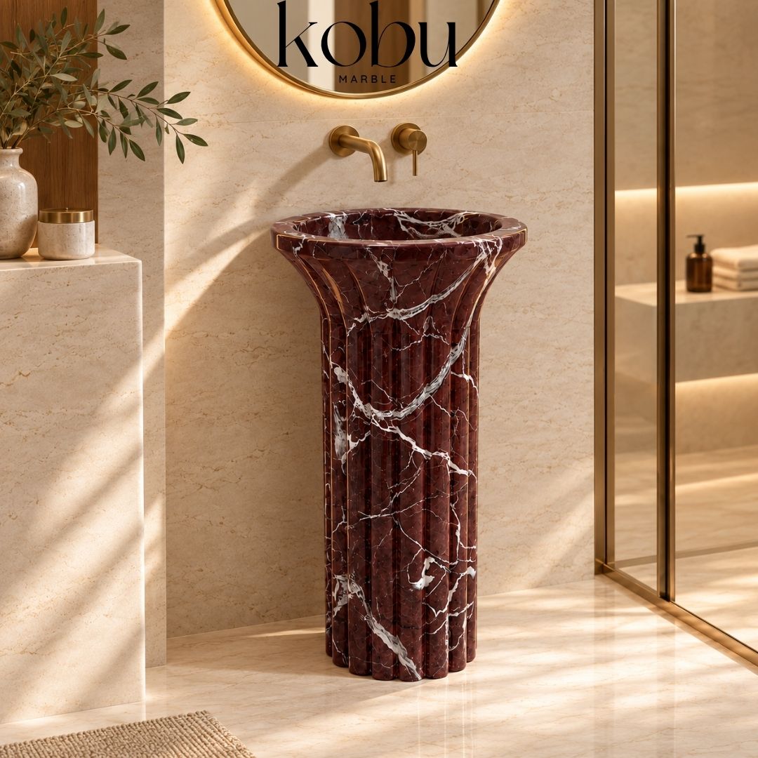 Handcrafted two-piece Rosso Levanto stone pedestal sink highlighting its sculptural marble basin and pedestal base.